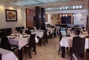 阿尔及尔DAR EL IKRAM HOTEL的用餐室配有白色桌子和黑色椅子