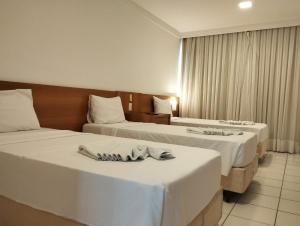 纳塔尔PONTA NEGRA FLAT APART的两张位于酒店客房的床,配有毛巾