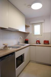 希俄斯Castrusso Castle apartments的厨房配有白色橱柜和水槽