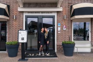 哈尔德韦克Restaurant & Hotel Monopole Harderwijk的两名妇女站在大楼门口