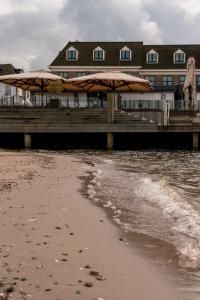 哈尔德韦克Restaurant & Hotel Monopole Harderwijk的海滩上带两把遮阳伞的码头