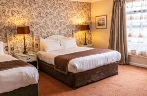 斯特拉诺勒Kee's Hotel的酒店客房设有两张床和窗户。