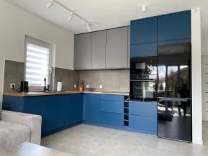 兰卡特Apartament Luna的厨房配有蓝色橱柜和黑色冰箱。