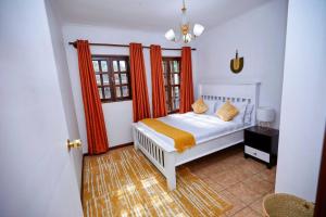 NgateuPeaceful and Cozy Home in Arusha的一间卧室配有白色的床和橙色窗帘