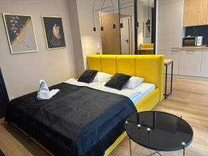 克拉科夫Tauron Arena Apartment with Garage - Kraków Lema的一间卧室配有一张带黄色床头板的床和一张桌子