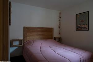 圣拉里苏朗Apparts au Cœur de St-Lary - Piscine Chauffée et Sauna的一间卧室配有一张粉红色的床和木制床头板