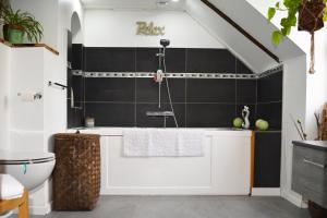 圣阿韦尔坦Manoir Drissia - Tours Centre, France的浴室设有白色浴缸和黑色瓷砖墙。