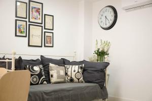 马德里Apartamento Ágüelos的客房设有带枕头的沙发和墙上的时钟