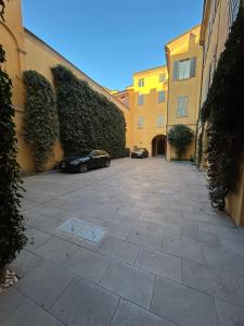 摩德纳Ferrari Suite Modena的两栋建筑之间的庭院里停泊的汽车