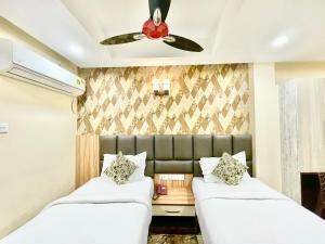 普里Hotel Yashasvi ! Puri fully-air-conditioned-hotel near-sea-beach-&-temple with-lift-and-parking-facility breakfast-included的配有吊扇的客房内的两张床