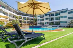 Ka RornSeaview Apartments - Karon Beach的一个带2把躺椅和遮阳伞的游泳池