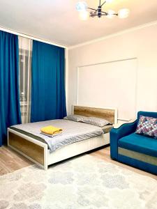 阿拉木图жк vostochkakz的一间卧室配有一张带蓝色窗帘的床和一张蓝色椅子