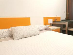 马里亚诺Habitación cerca del aeropuerto的一间卧室配有一张白色的床和橙色的墙壁