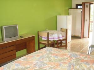 因巴塞Imbassai Flat的一间卧室配有一张床、一张桌子和一台电视。