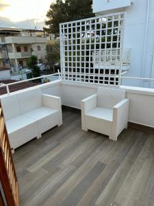 吉诺萨滨海B&B Il Timone - Ginosa Marina的阳台配有两把白色椅子和窗户。