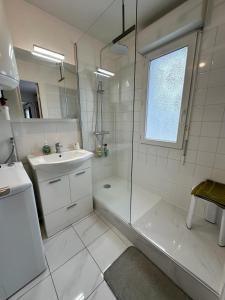 奥贝维利埃Chez Daniel, un 2 pièces proche de Paris STADE de FRANCE的带淋浴和盥洗盆的白色浴室