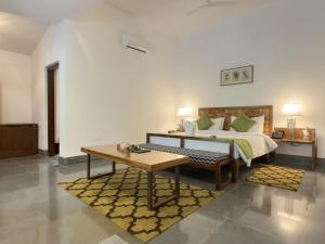 加尔加Saraca Resort & Spa Corbett的一间卧室配有一张带桌子和长凳的床