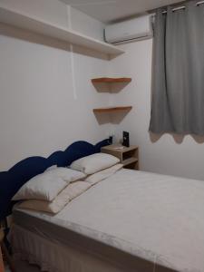 萨尔瓦多Casa em Village com piscina e perto da praia的一间卧室配有一张带白色床单的床和一扇窗户。
