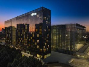 罗马Hilton Rome Eur La Lama的一座高大的玻璃建筑,上面有黑尔顿标志