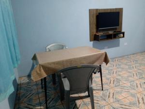 瓜鲁柳斯Quarto familiar, aeroporto Guarulhos的一张桌子、两把椅子和一台电视机