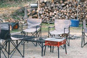 一軒家貸切 ARUYOguesthouse BBQと焚き火ができる宿的一堆木头前面的一组椅子和一张桌子