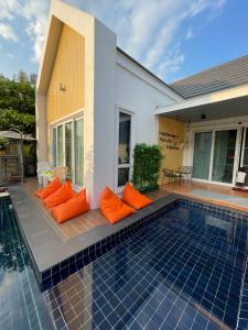 乌隆他尼Pool Villa Udonthani的一座带橙色枕头的游泳池位于房子旁边