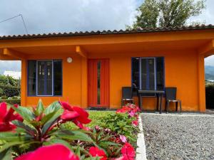 佩雷拉Life is Beautiful! Cottage in the Nature的一座橙色的小房子,两把椅子和鲜花