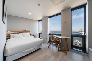束草市Stay Hostel的卧室配有床、桌子和窗户。