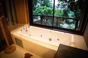 Ban Tha ChangKhaoyai Kirimaya Atta Residence 5 BR Villa的窗户客房内的浴缸