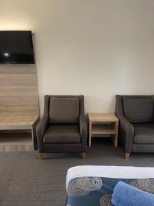 扬巴扬巴阿斯顿汽车旅馆的酒店客房配有2把椅子和平面电视。