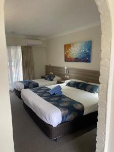 扬巴扬巴阿斯顿汽车旅馆的酒店客房设有两张床,墙上挂有绘画作品