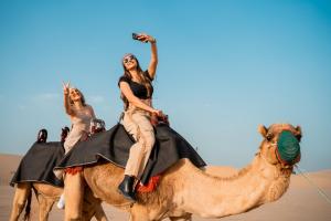 HunaywahDesert Safari Overnight Experience "Modern room with AC & Entertainment"的两个在沙漠骑骆驼的女人