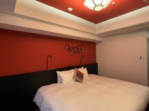 大阪Hotel Dans Le Coeur Osaka Umeda的卧室配有白色的床铺和红色的墙壁