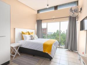 比勒陀利亚Leas Furnished Apartments - Capital Hill的一间卧室设有一张床和一个大窗户