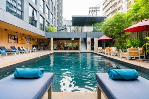 曼谷Galleria 12 Sukhumvit Bangkok by Compass Hospitality的一座带蓝色枕头的建筑中的游泳池