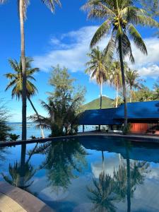 美翰Cozy house in Chaloklum的棕榈树和海洋的游泳池