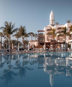 普拉亚布兰卡杨扎公主套房度假酒店的一座带游泳池的度假村,位于一座建筑前
