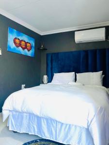察嫩Executive Galaxy Guest House Nkowankowa Extension 2的卧室内的白色床和蓝色的墙壁