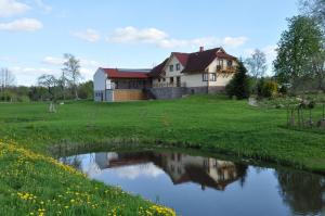 SukturiViesu nams Bezdubeņi的前面有池塘的房子