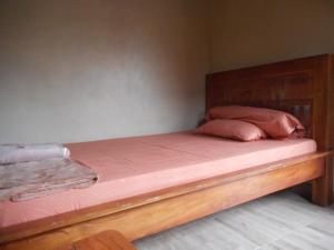 BesakihKadek Homestay的一张带木架和粉红色床单及枕头的床