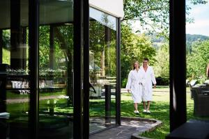 新波南特格尼斯可杰霍夫山温泉度假酒店的白人男子和女子穿过玻璃门
