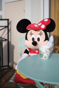 马尼库尔勒翁格尔Apart' Minnie - Disneyland Paris - 3 Bedrooms - Parking privé的坐在桌子上拿着杯子的微型老鼠玩具