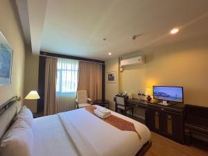 彭世洛Wangchan Riverview的酒店客房配有一张床、一张书桌和一台电视。