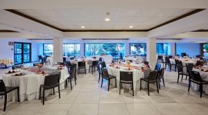 罗列特海岸桑巴酒店的宴会厅配有白色的桌椅和窗户