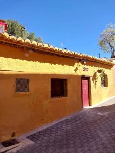 PedralbaLa casita del Horno的黄色建筑,有红门和砖车道