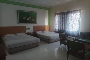 井里汶Permata Hijau的酒店客房设有两张床、一张书桌和一个窗户。