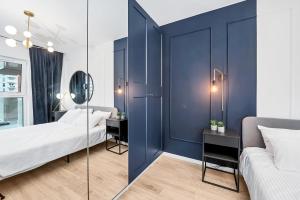 罗兹Lumina 2-room apartment with beautiful view Lodz的一间卧室设有蓝色的墙壁、两张床和镜子