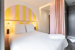 南特DEMAIN Hôtel & Conciergerie的一间卧室配有一张白色大床和色彩缤纷的床头板