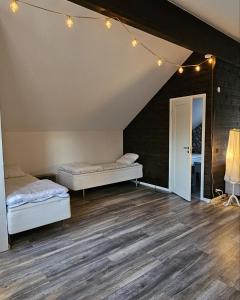 斯特伦斯塔德Guesthouse Erlandseröd的配有2张床的客房,设有木地板和灯