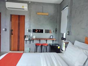 北碧Cicada Hotel Kanchanaburi的一间卧室配有一张床和两张红色凳子